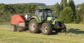 BIO+ haciendo pacas en un paisaje austriaco con árboles al fondo.
