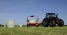 Encintadora de pacas redondas RW 1800 encintando pacas en un campo.