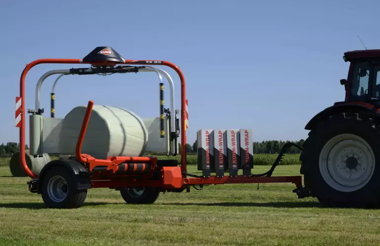Encintadora de pacas redondas RW 1800 encintando pacas en un campo.