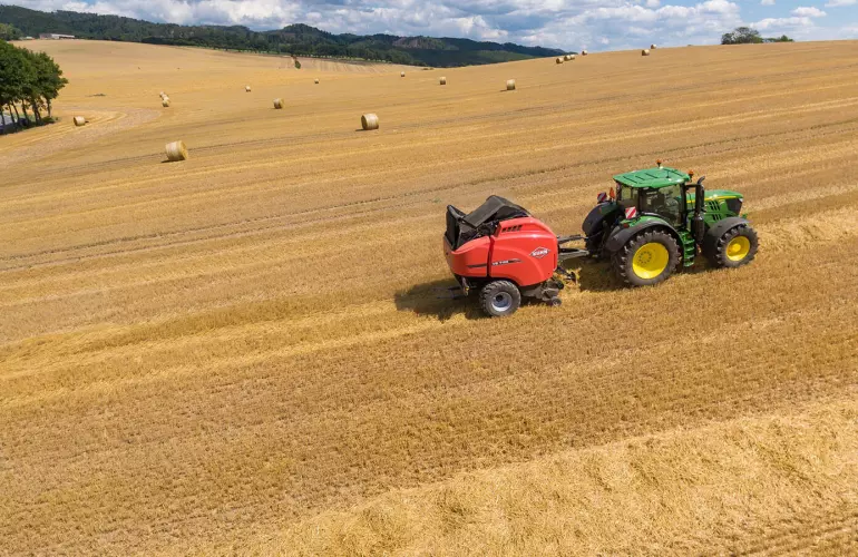 Vista general de una empacadora VB 7190 en un campo de paja con fardos redondos bajo un bonito cielo