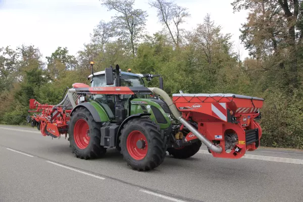 Conjunto de tractor y máquina equipado con una tolva frontal TF 1512 con reparto de cargas durante el transporte